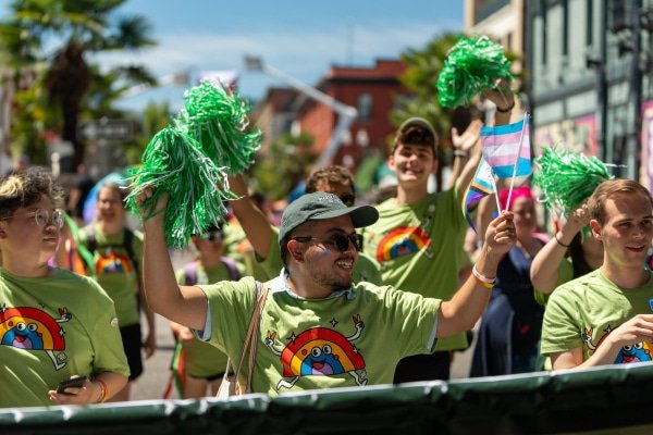 alumni hold pom poms and cheer while walking in the Portland Pride Parade