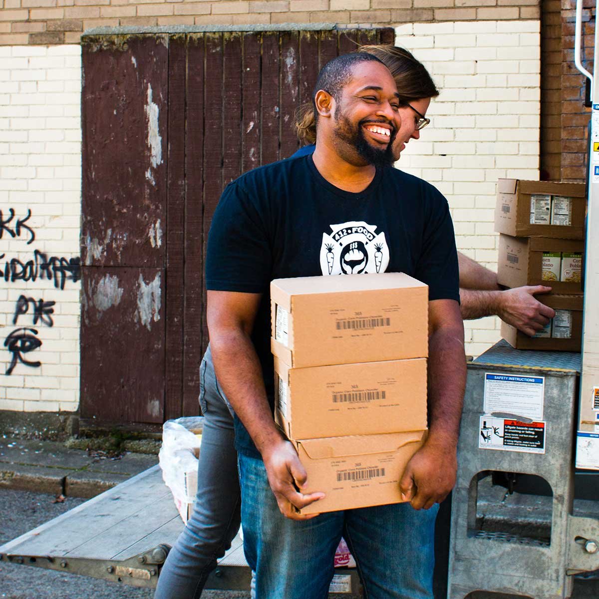 Man wearing a 412 Food Rescue t-shirt unloading boxes of rescued food.