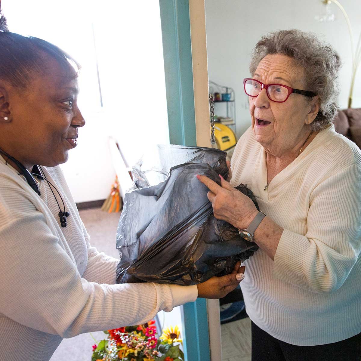 Woman delivering a grocery bag of food to an elderly woman